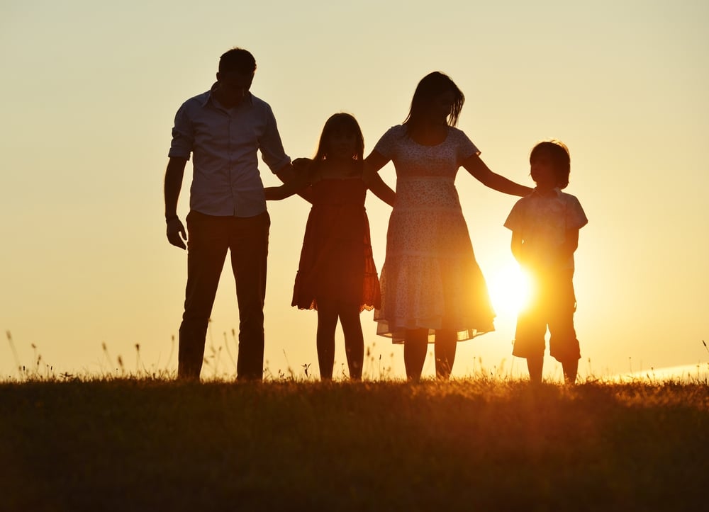 People silhouettes on summer sunset meadow